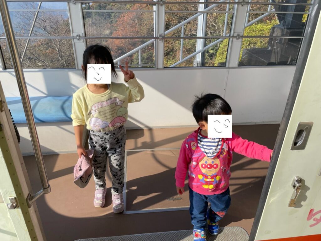 Two children riding a gondola ride on the ropeway riba in Ohirayama Summit Park